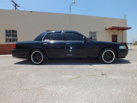 2003 Ford Crown Victoria - Profile of blacked-out Crown Vic with brush guard, tinted windows, sunny lot.
