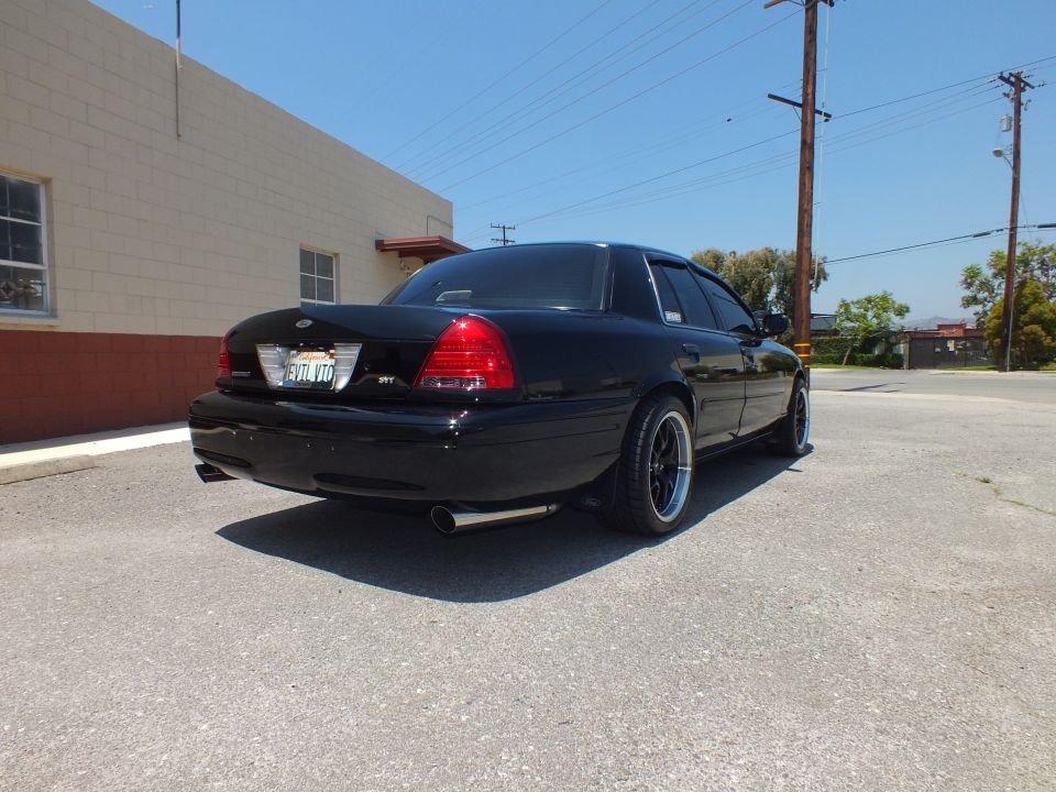 Rear of black Crown Victoria SVT with dual exhaust beside building
