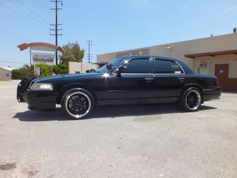 2003 Ford Crown Victoria - Profile of blacked-out Crown Vic with brush guard, chrome-lip wheels, sunny day.
