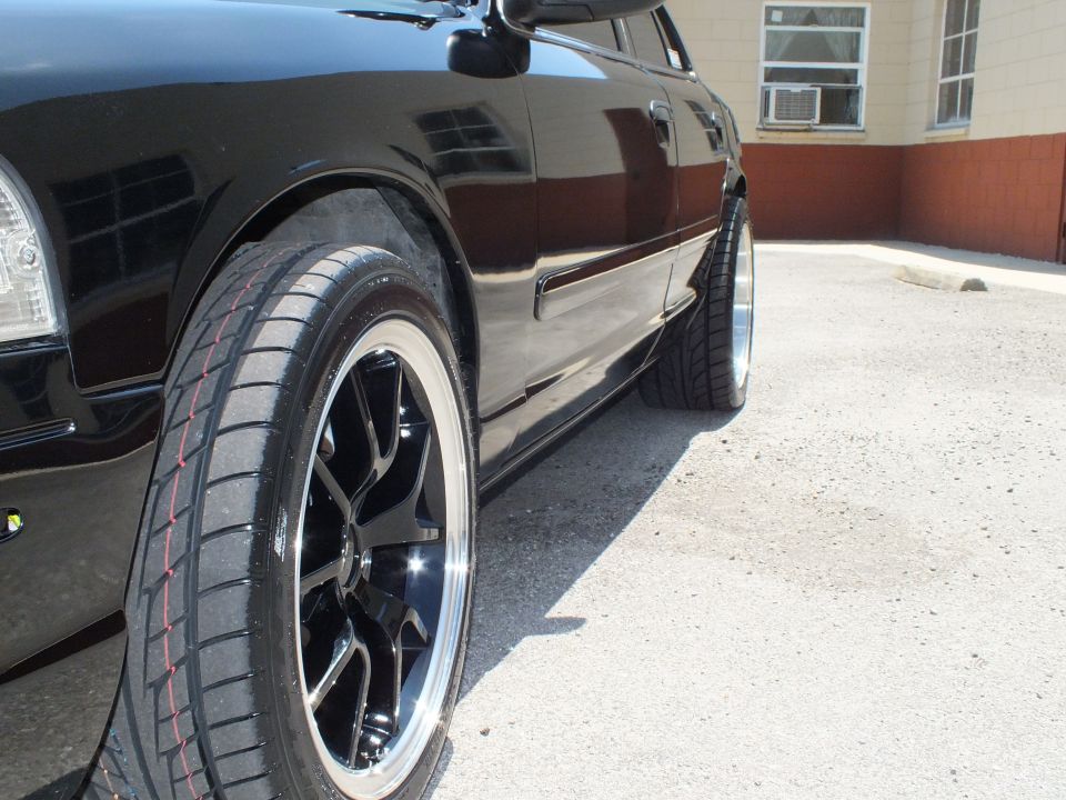 Close-up of black multi-spoke wheel with chrome lip on black Crown Victoria
