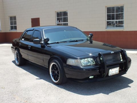2003 Ford Crown Victoria - Front three-quarter of a black Ford sedan fitted with a push-bar grille guard, spotlight and EVIL VTC plate.