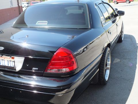 2003 Ford Crown Victoria - Rear quarter of a black Ford sedan with SVT taillight badge and California EVIL VTC license plate.