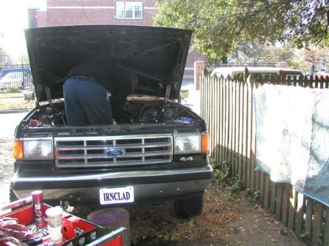 1988 Ford Bronco - A 1988 Ford Bronco is shown with its hood open as someone works on the engine, parked outdoors.