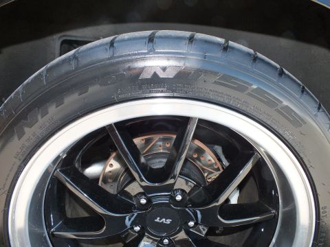 2003 Ford Crown Victoria - Close-up of an SVT-capped black wheel, Nitto NT555 tire and cross-drilled brake rotor.