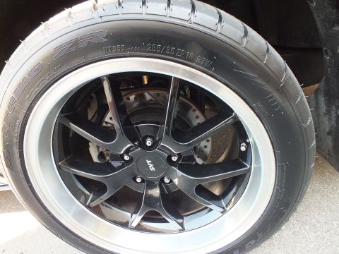 2003 Ford Crown Victoria - SVT-capped black machined-lip wheel wearing an Extreme ZR 285/35 ZR18 tire over a drilled rotor.