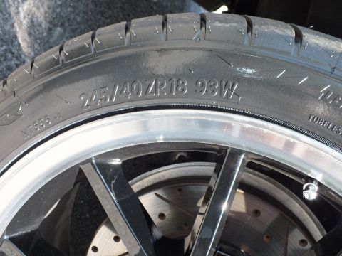 2003 Ford Crown Victoria - Close view of a tire sidewall marked 245/40 ZR18 93W on a polished wheel over a drilled rotor.