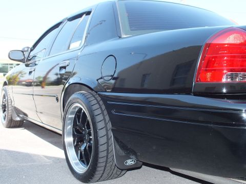2003 Ford Crown Victoria - Rear quarter of a lowered black Ford sedan with black polished-lip wheel, taillight and Ford mud flap.
