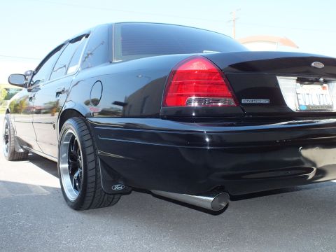 2003 Ford Crown Victoria - Low rear-quarter view of a black Police Interceptor with Ford mud flap and angled chrome exhaust tip.