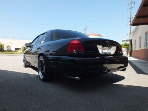 2003 Ford Crown Victoria - Low-angle rear three-quarter of a black Crown Victoria with California plate and dual chrome exhaust tips.
