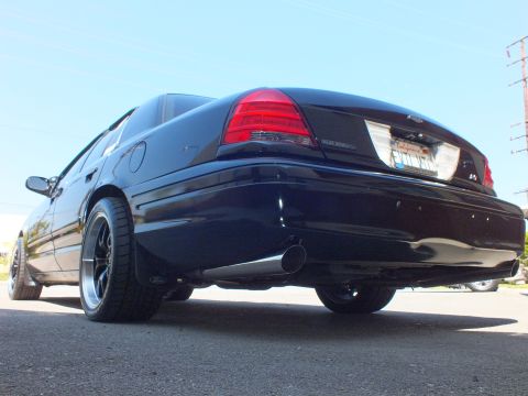 2003 Ford Crown Victoria - Ground-level rear shot of a black Crown Victoria, taillights and twin chrome exhaust tips in focus.