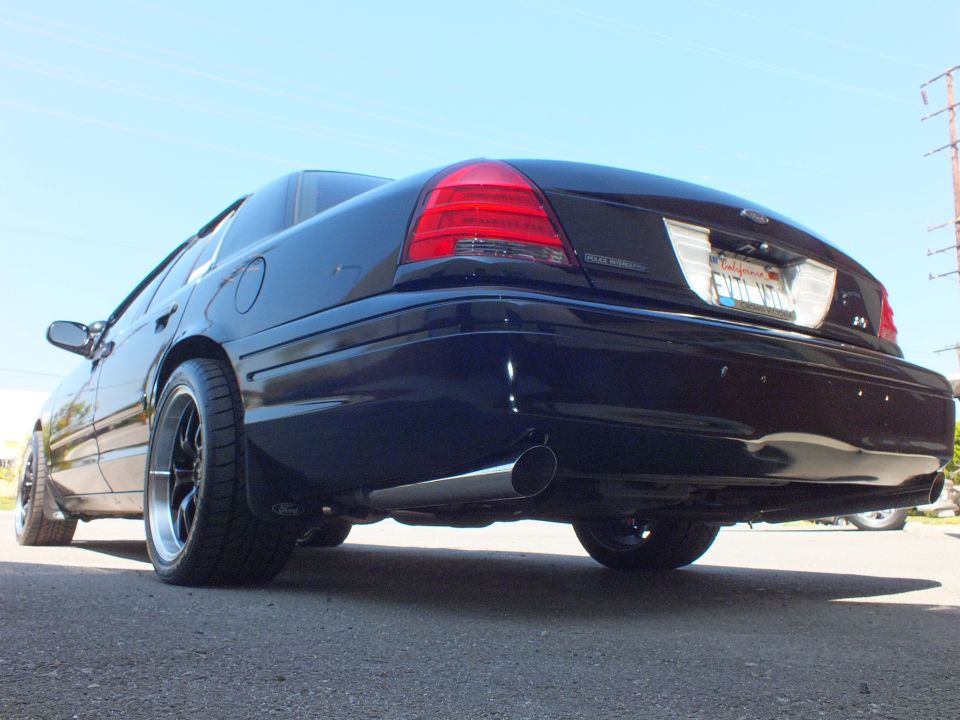 Black Ford Crown Victoria rear low-angle view with chrome exhaust tips and black wheels