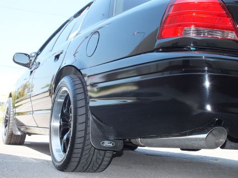 2003 Ford Crown Victoria - Tight rear-quarter view of a black Crown Victoria, glossy panel reflecting light above black machined wheel.
