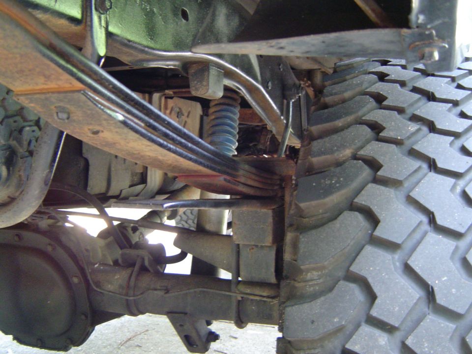 Close-up of truck's rear leaf springs, shock absorber, and aggressive tread tire