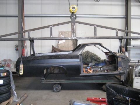 1973 Ford Ranchero - The car body is suspended by a metal frame and crane in a workshop.