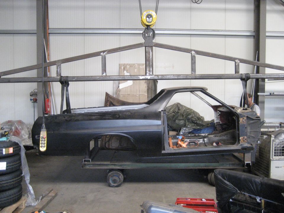 car body on a lift, interior gutted, covered with tarps