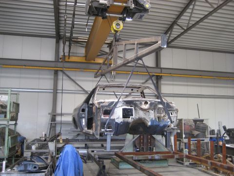 1973 Ford Ranchero - Car body undergoing restoration in a workshop, lifted by a large industrial crane.