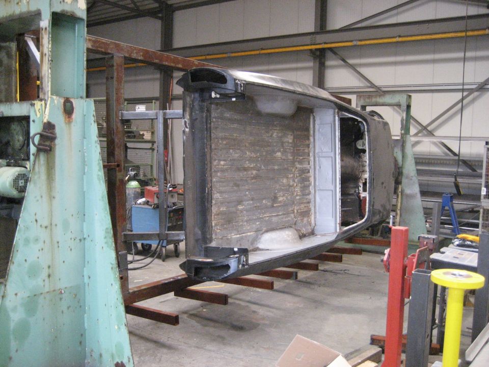 Upside-down vehicle body in workshop, undergoing repairs