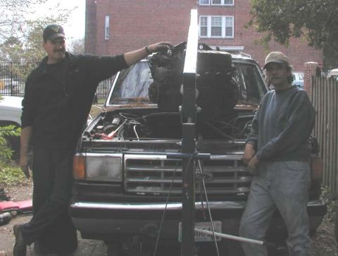 1988 Ford Bronco - Two men work on a Ford Bronco, its hood open, with an engine hoist nearby.