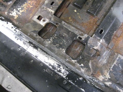 1973 Ford Ranchero - Close-up of a rusted vehicle floor pan with stamped part numbers visible.