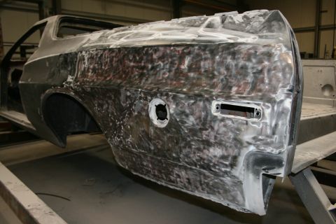 1973 Ford Ranchero - The rear quarter panel of a vehicle is undergoing bodywork, revealing bare metal and primer.