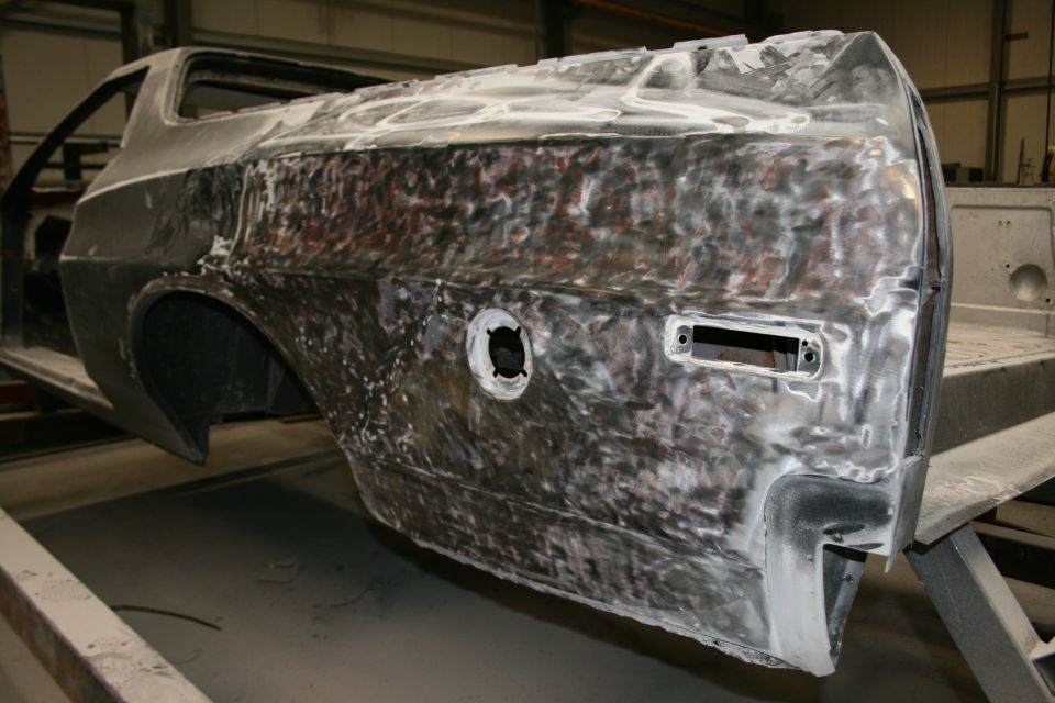car body with bare metal and primer, showing fuel door and taillight housing