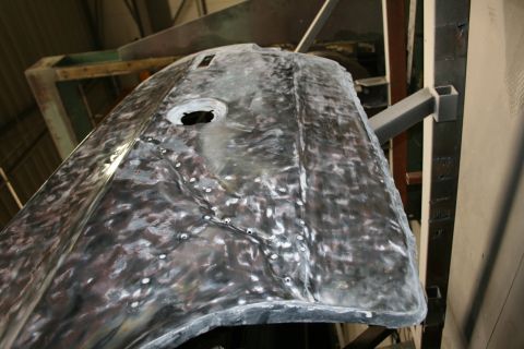 1973 Ford Ranchero - A car hood is shown in a state of repair, with visible metalwork and numerous rivets.