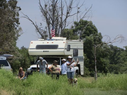 1968 Ford Mustang - An RV is parked in a field with several people and a dog nearby.