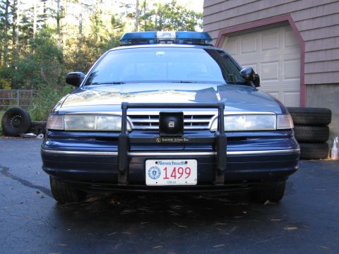 2001 Ford Crown Victoria - Front view of a blue police car, likely a 2001 Ford Crown Victoria, equipped with a push bar and emergency light bar.