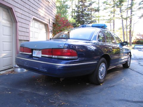 2001 Ford Crown Victoria - Rear view of a blue police car, possibly a 2001 Ford Crown Victoria, with a two-tone paint scheme and a visible license plate.