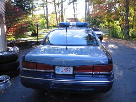 2001 Ford Crown Victoria - 2001 Ford Crown Victoria police car with light bar, parked in a driveway with autumn trees.