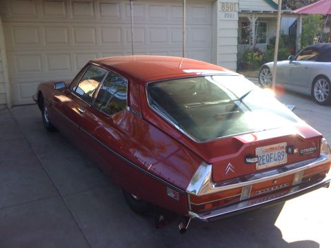 1968 Ford Mustang - A red Citroën SM is parked in front of a garage, with another car visible in the background.