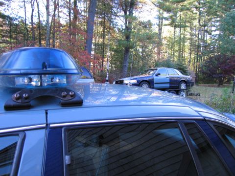 2001 Ford Crown Victoria - A police car with a light bar is in the foreground, with another police car on a trailer behind it.