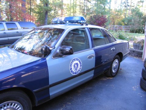 2001 Ford Crown Victoria - A 2001 Ford Crown Victoria police car is parked outdoors next to a silver SUV.