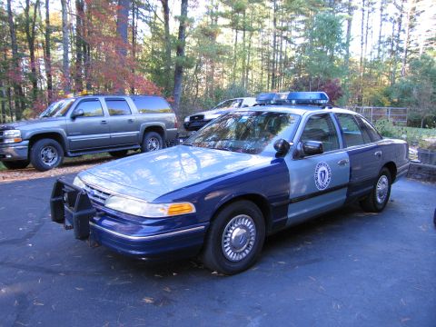 2001 Ford Crown Victoria - A 2001 Ford Crown Victoria police car is parked in a driveway with a Chevrolet Suburban in the background.