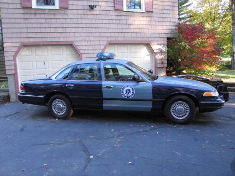 2001 Ford Crown Victoria - A 2001 Ford Crown Victoria police car is parked in front of a house with two garage doors.