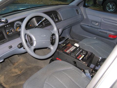 2001 Ford Crown Victoria - The interior of a 2001 Ford Crown Victoria police car, equipped with a radio console and other law enforcement equipment.
