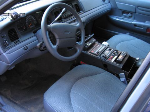 2001 Ford Crown Victoria - The interior of a police car, equipped with communication devices and a standard dashboard layout.
