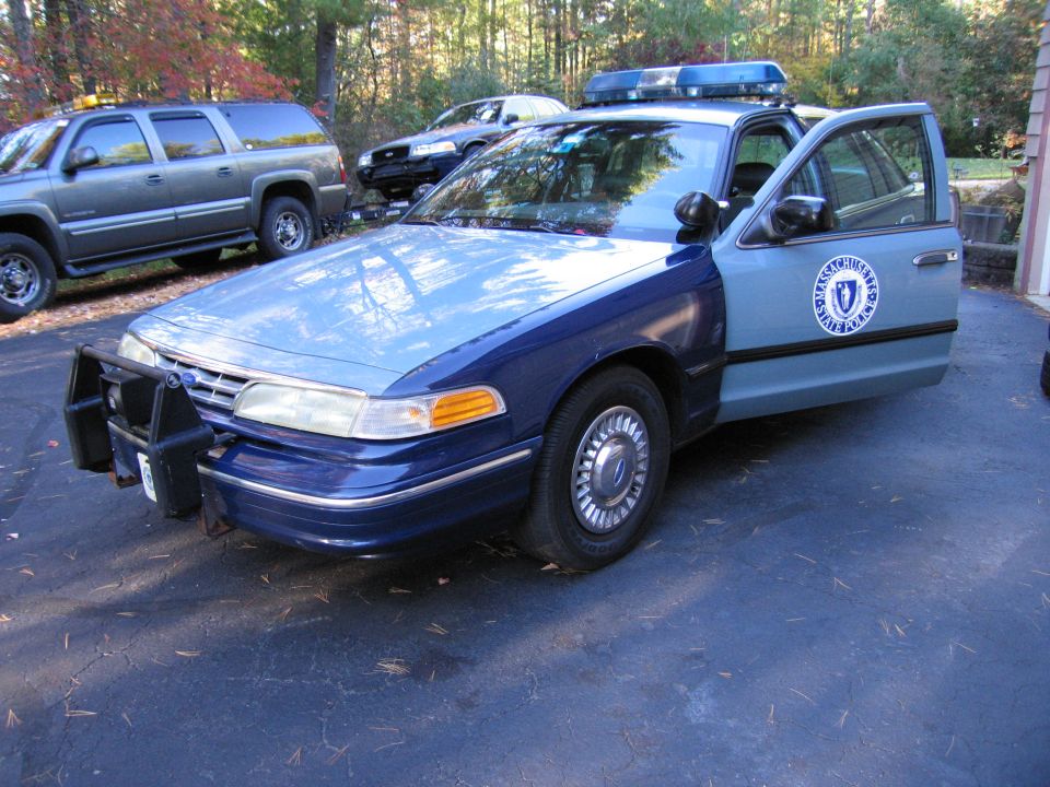 Blue and grey police car, front quarter view, with Massachusetts State Police emblem on door