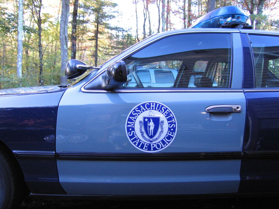 Side view of a two-tone blue 2001 Ford Crown Victoria police car with a Massachusetts State Police emblem on the door