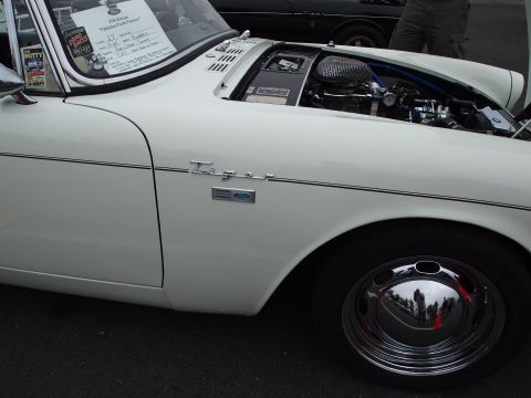 1994 Ford Bronco - A white sports car with its hood open, revealing the engine, is parked next to another vehicle.