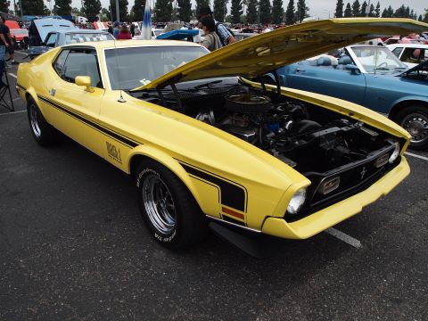 1994 Ford Bronco - A yellow 1971 Ford Mustang Mach 1 is displayed with its hood open, revealing the engine bay.