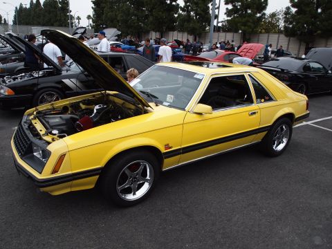 1994 Ford Bronco - A yellow Ford Mustang is displayed with its hood open at an outdoor car event.