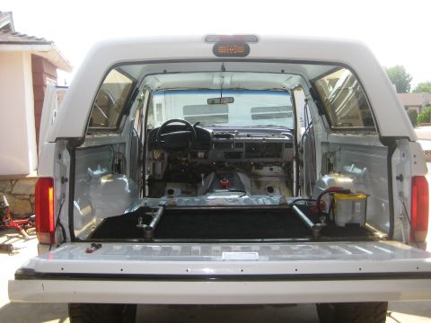 1996 Ford Bronco - The interior of a white Ford Bronco is visible with the dashboard disassembled and the cargo area cleared out.