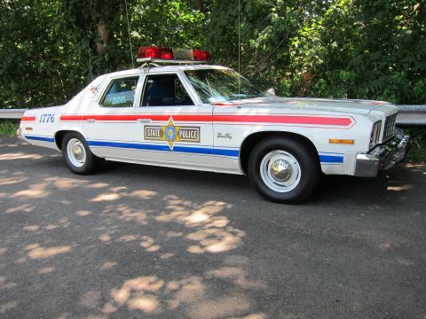 1991 Ford LTD Crown Victoria - white State Police sedan decorated with red and blue stripes and a 1776 bicentennial marking, parked on pavement.