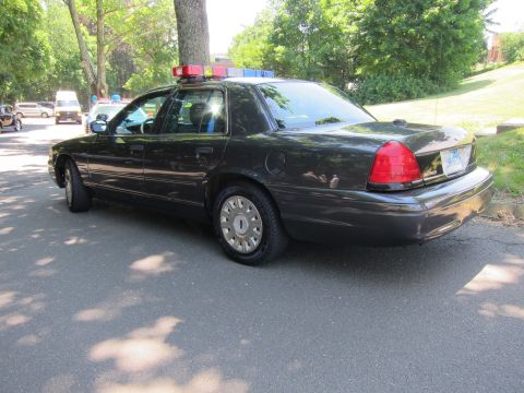 1991 Ford LTD Crown Victoria - Rear three-quarter view of a dark gray unmarked police sedan with a low-profile rooftop lightbar, parked on a street.