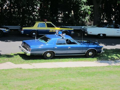 1991 Ford LTD Crown Victoria - blue classic police sedan parked beside a yellow-and-blue State Police cruiser on a grassy show field.