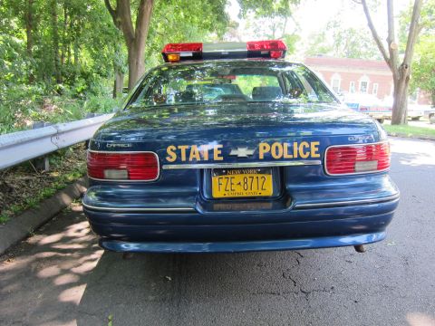 1991 Ford LTD Crown Victoria - Rear view of a dark blue Chevrolet Caprice marked STATE POLICE with a red lightbar and a yellow New York Empire State license plate FZE-871…