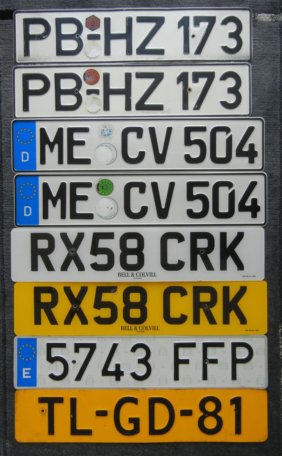 Stack of license plates with various markings and numbers
