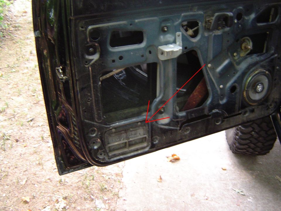 Car door interior with visible speaker and window mechanism, showing rust and dirt