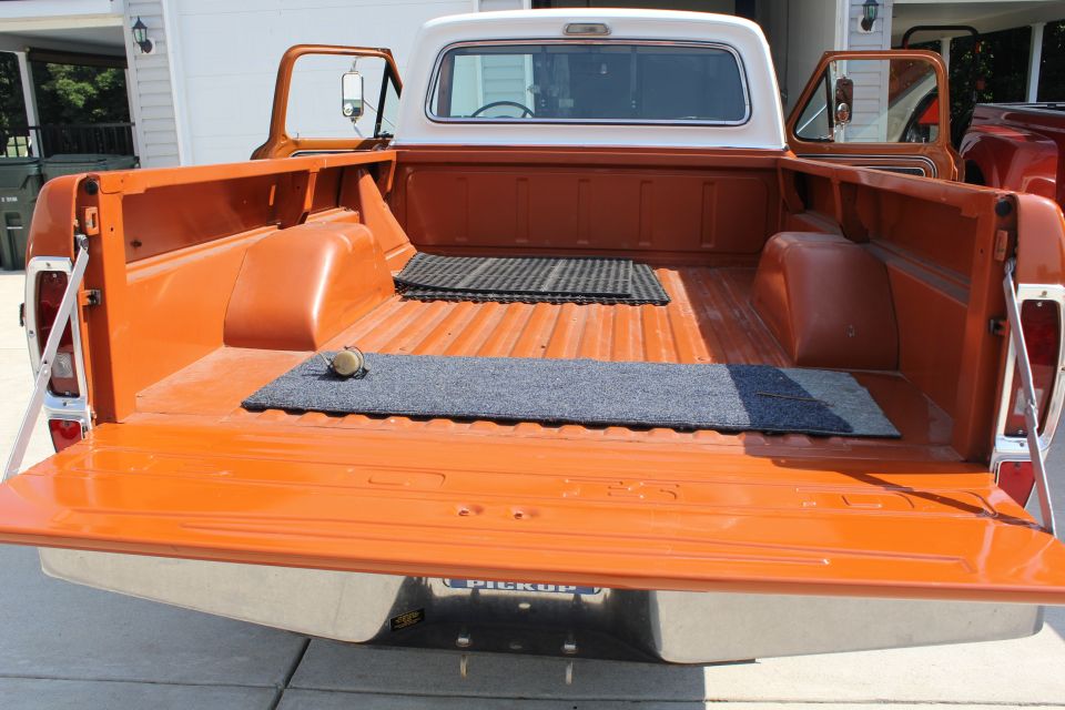 Orange pickup truck bed with tailgate down, white cab, and open doors
